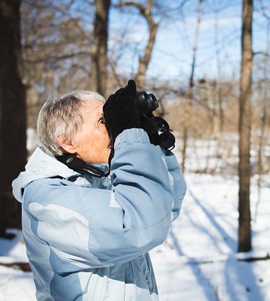 Woman looking through binoculars in winter