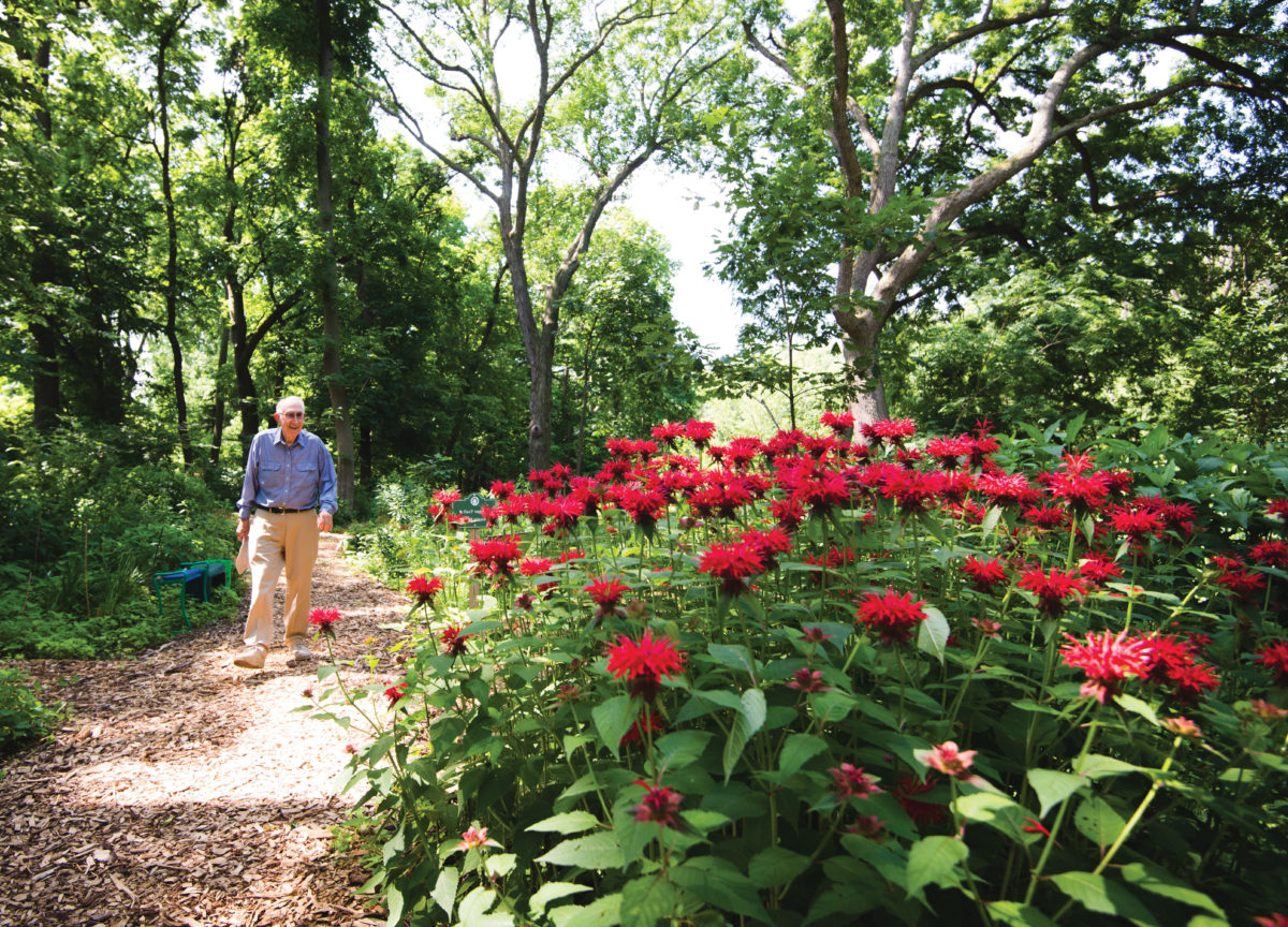 Man walking in woods with red flowers